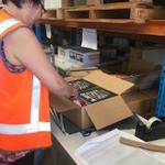 Female employee wearing high-vis vest packing an order of books into a brown box